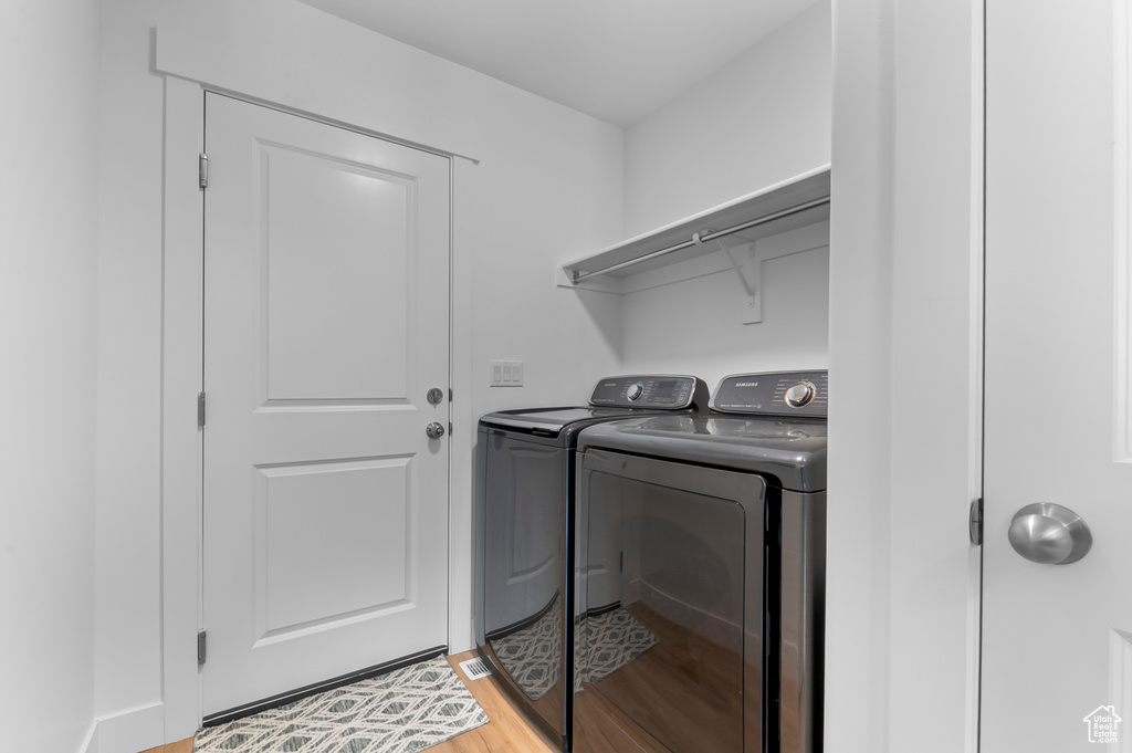 Washroom featuring washer and clothes dryer and light wood finished floors