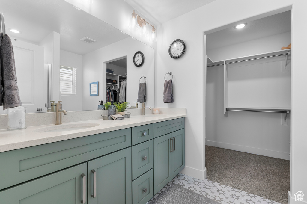 Full bathroom featuring double vanity, a walk in closet, baseboards, and recessed lighting