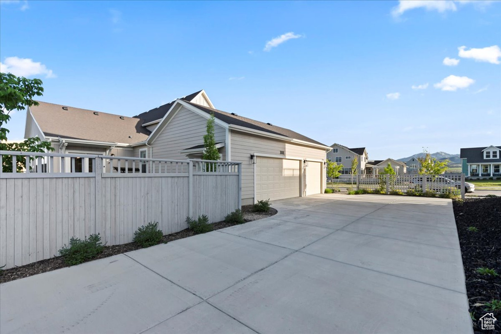 View of property exterior with fence, a residential view, and driveway