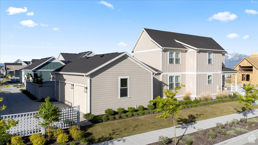 View of side of property featuring board and batten siding, an attached garage, a residential view, and fence