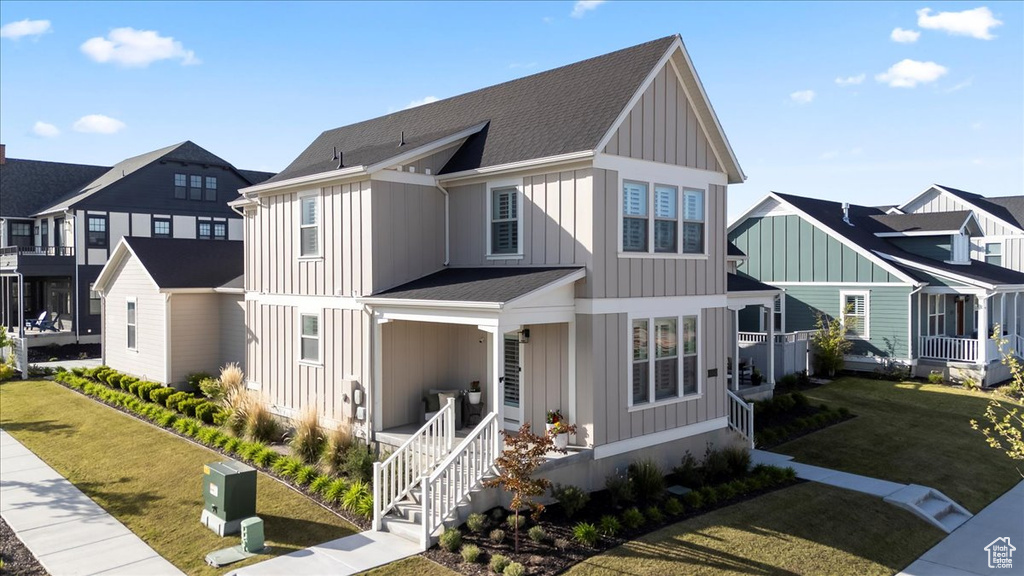 View of front facade featuring board and batten siding, covered porch, a residential view, and a front yard
