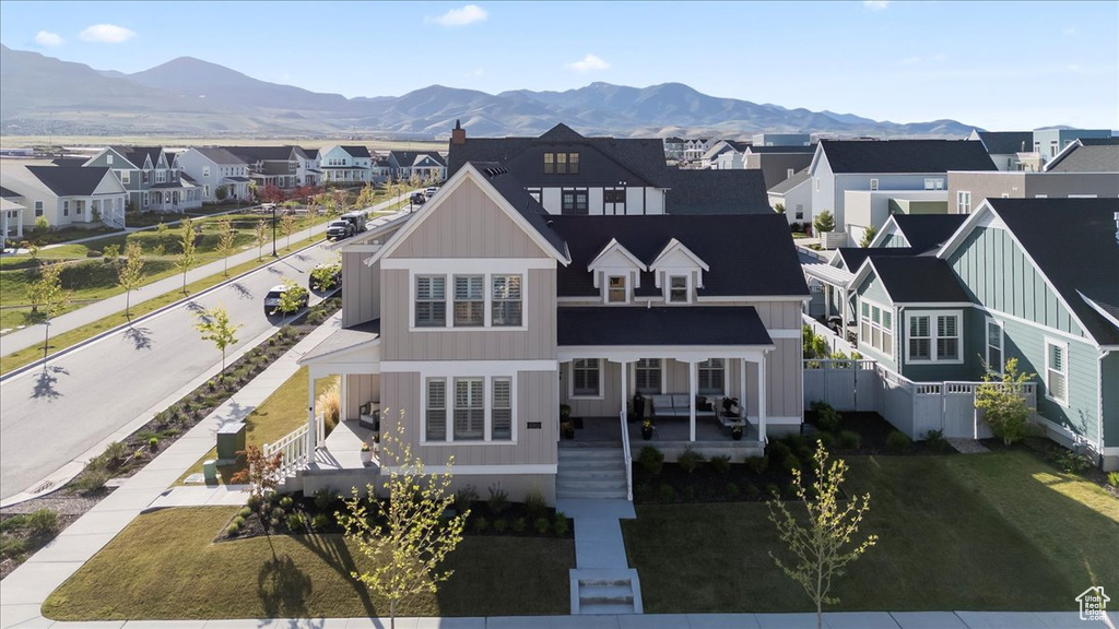 View of front facade with board and batten siding, a residential view, a mountain view, fence, and a porch