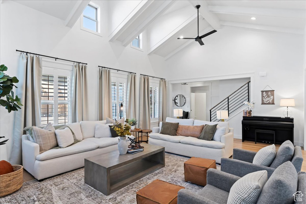 Living room featuring high vaulted ceiling, beamed ceiling, plenty of natural light, stairway, and wood finished floors