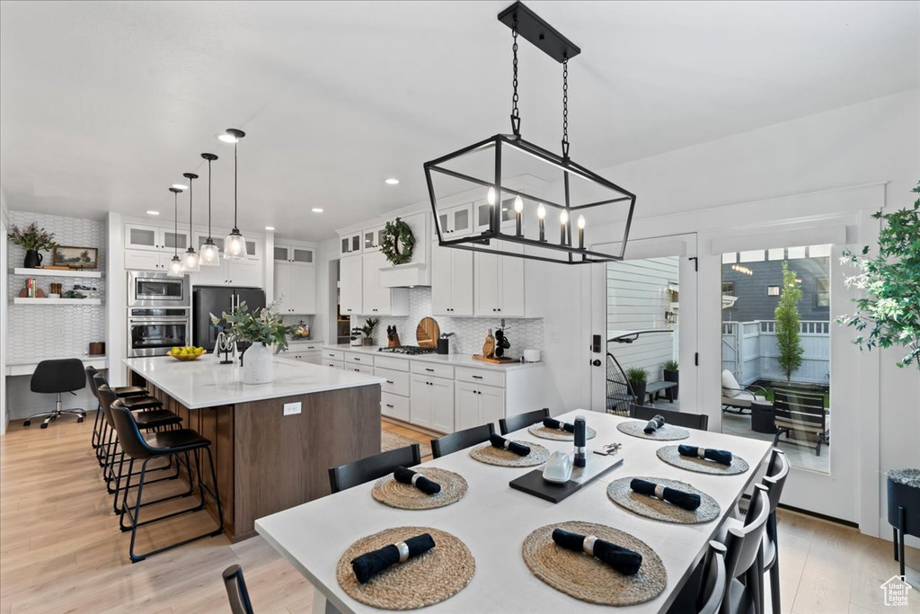 Dining room featuring light wood-type flooring, a chandelier, recessed lighting, and a desk