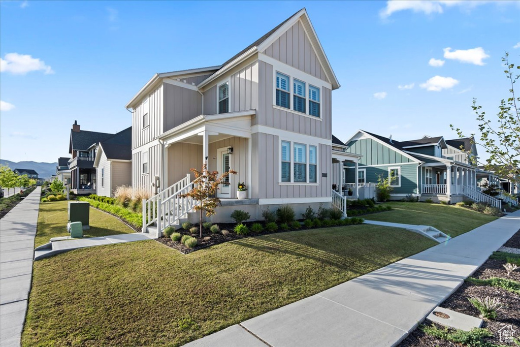 View of front of home with board and batten siding, a residential view, a front lawn, and covered porch