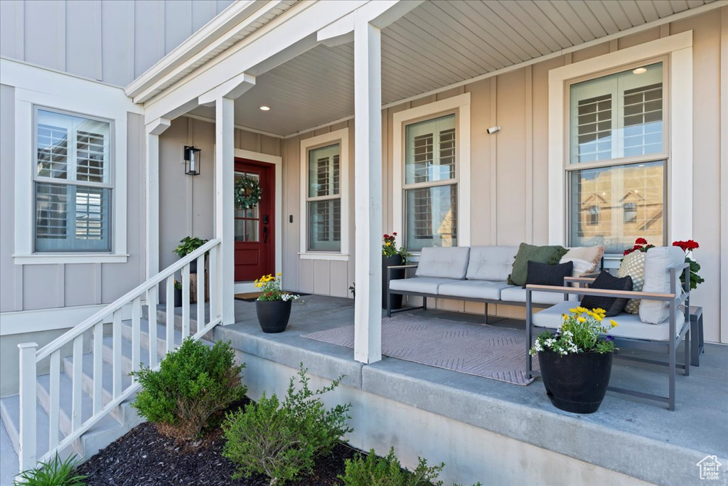Doorway to property featuring board and batten siding, covered porch, and outdoor lounge area