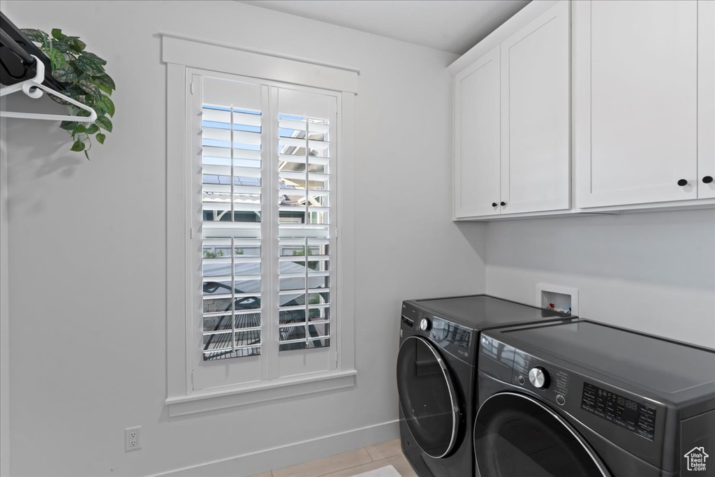 Laundry room with cabinet space, washer and dryer, baseboards, and tile patterned floors