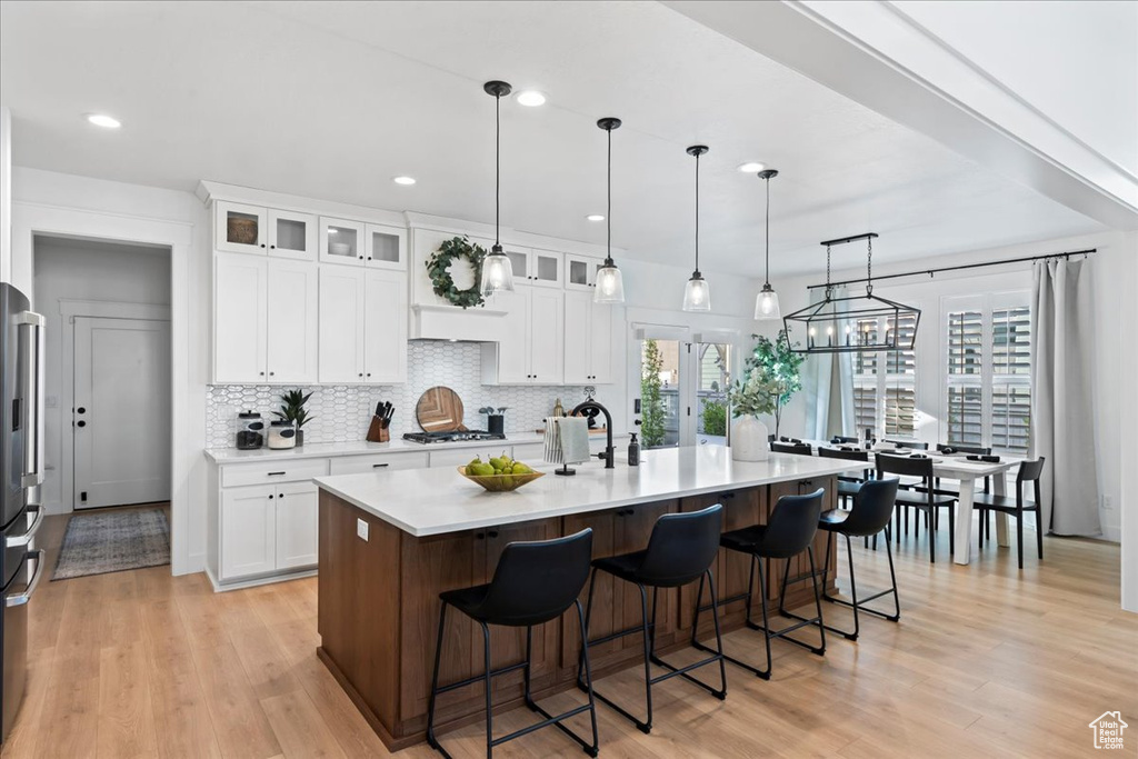 Kitchen featuring tasteful backsplash, light countertops, gas stovetop, light wood finished floors, and recessed lighting