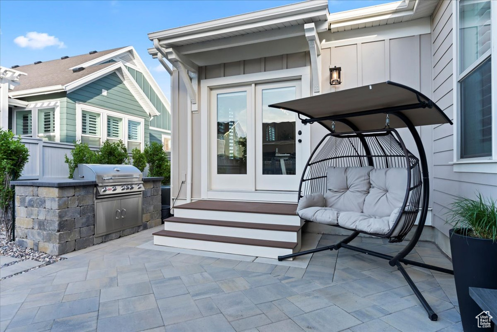 Property entrance featuring board and batten siding, exterior kitchen, french doors, and a patio area