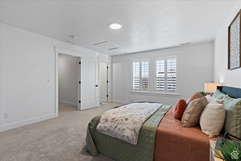 Bedroom featuring attic access, carpet flooring, and baseboards