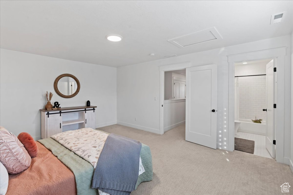 Bedroom with light colored carpet, attic access, baseboards, and ensuite bathroom