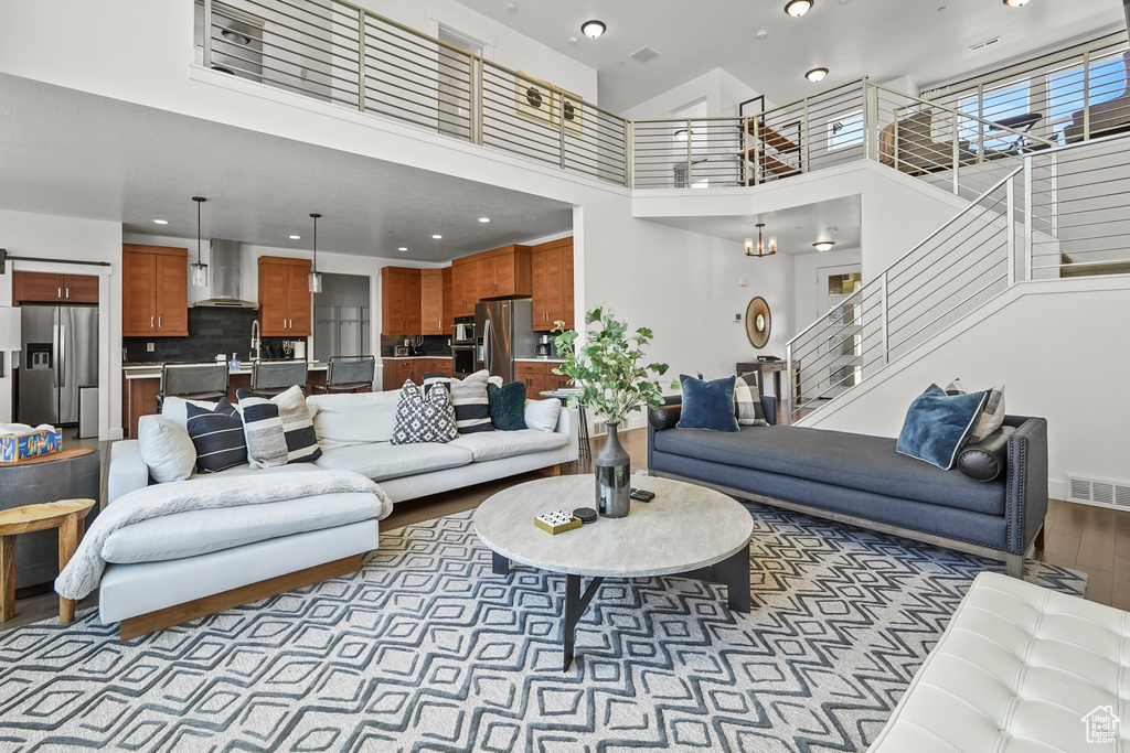 Living area with a high ceiling, wood finished floors, stairway, recessed lighting, and baseboards