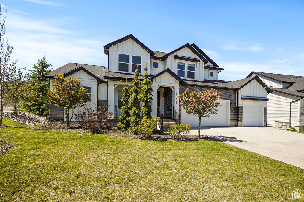 View of front of house with board and batten siding, driveway, a garage, a front yard, and a shingled roof