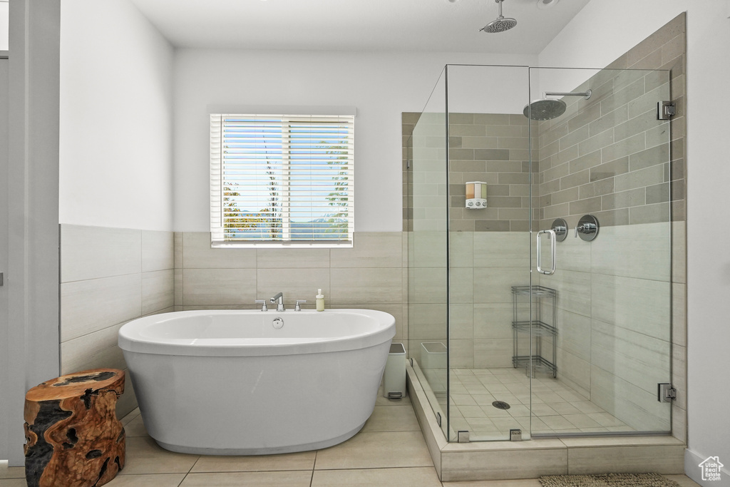 Bathroom featuring a stall shower, a freestanding tub, tile patterned flooring, tile walls, and a wainscoted wall