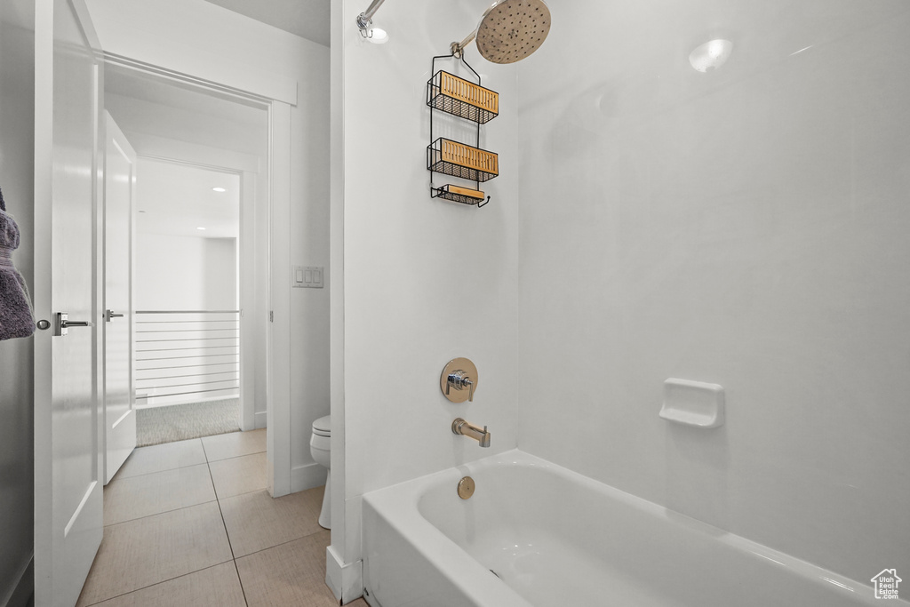 Full bathroom featuring toilet, tile patterned floors, and  shower combination