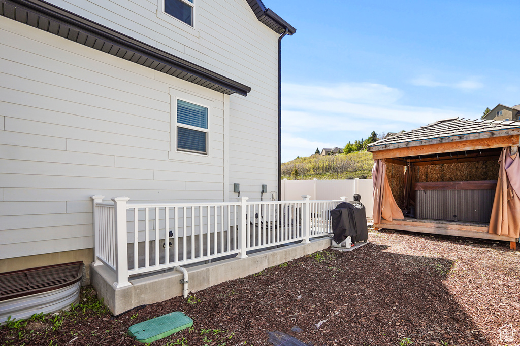 View of property exterior with a hot tub and fence