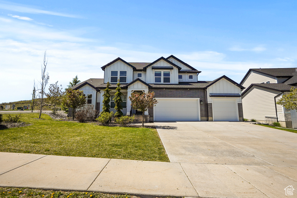 View of front of house featuring board and batten siding, concrete driveway, a front lawn, and an attached garage