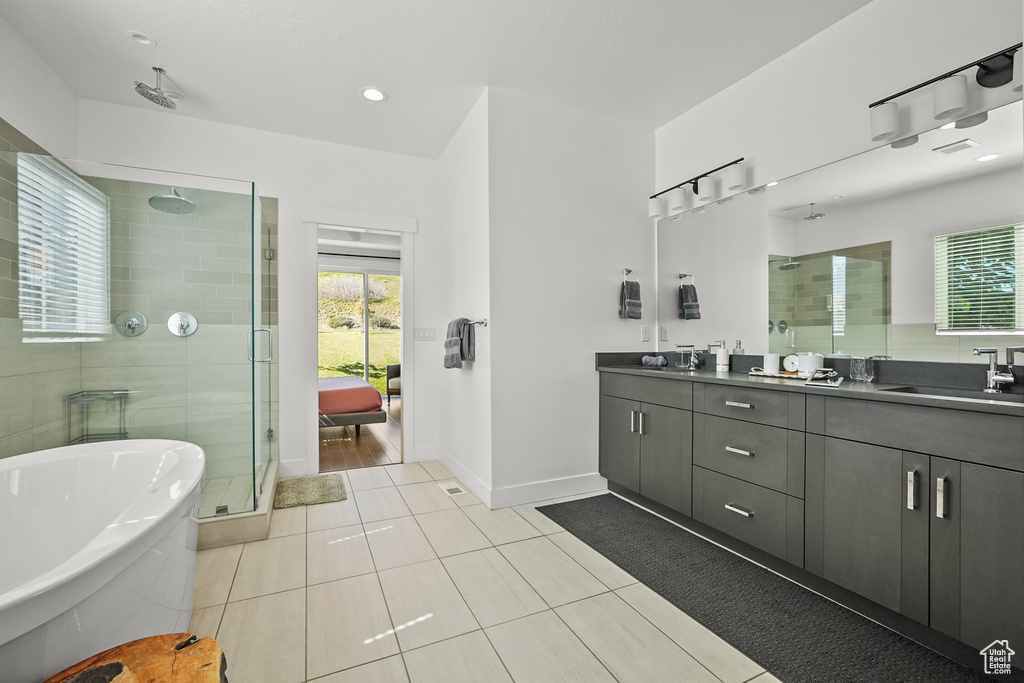 Bathroom with a shower stall, double vanity, tile patterned flooring, and healthy amount of natural light