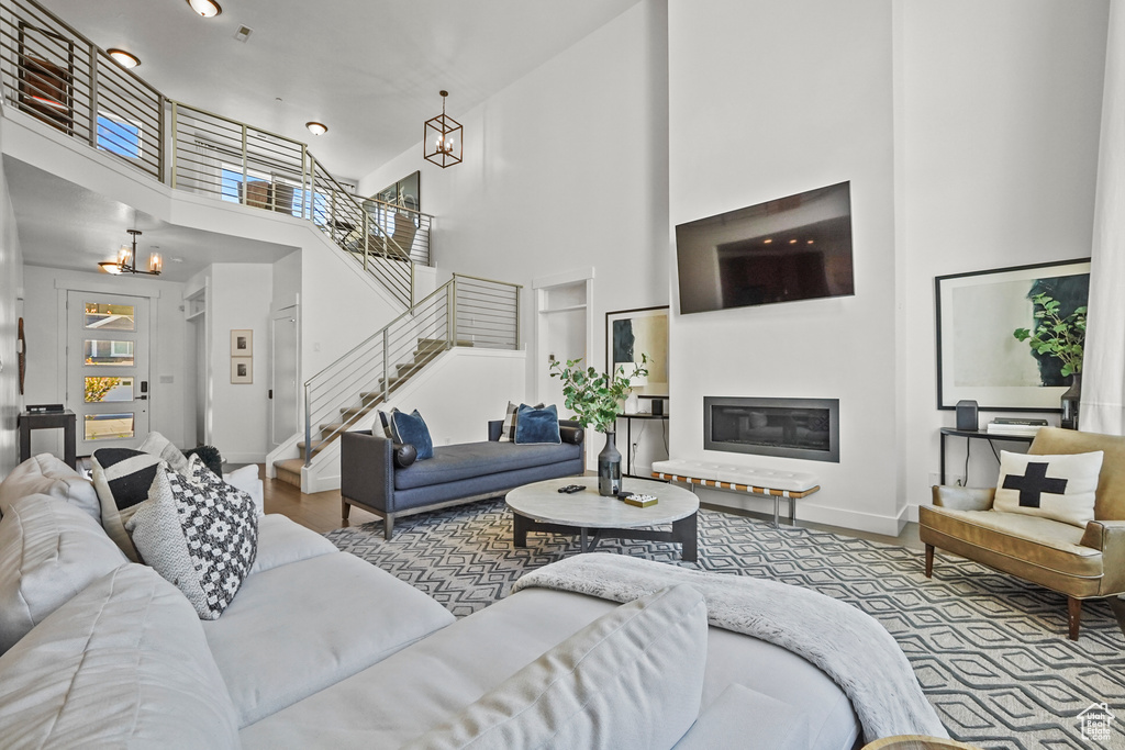 Living room with a chandelier, a high ceiling, stairway, baseboards, and a glass covered fireplace
