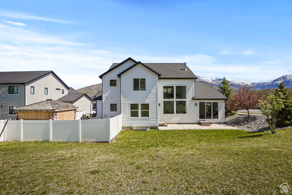 Back of house with a patio area, roof with shingles, and a mountain view