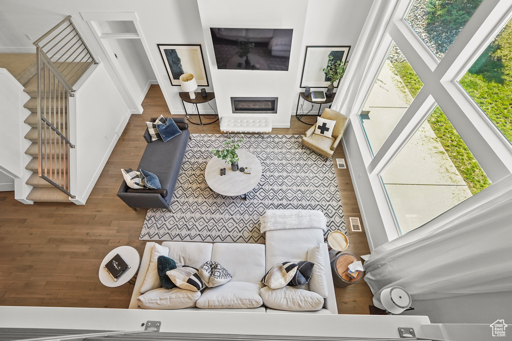 Living area with wood finished floors, stairs, a glass covered fireplace, and baseboards