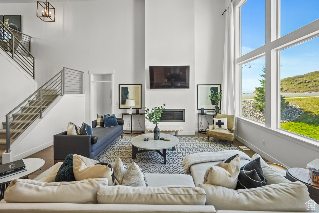 Living room featuring a towering ceiling, baseboards, wood finished floors, and stairway
