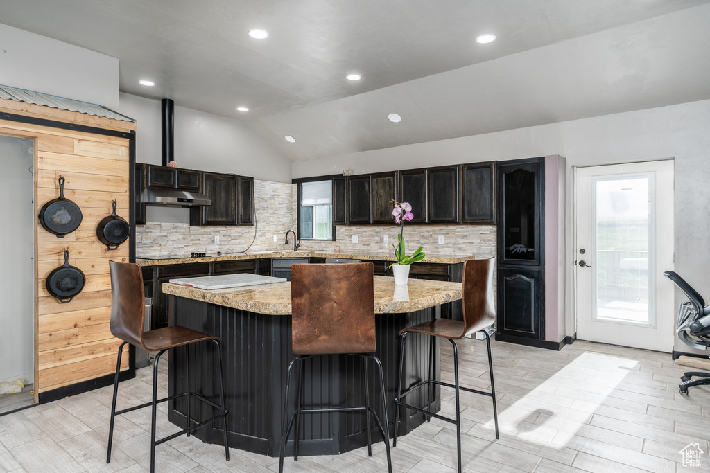 Kitchen with a kitchen breakfast bar, backsplash, vaulted ceiling, a kitchen island, and recessed lighting