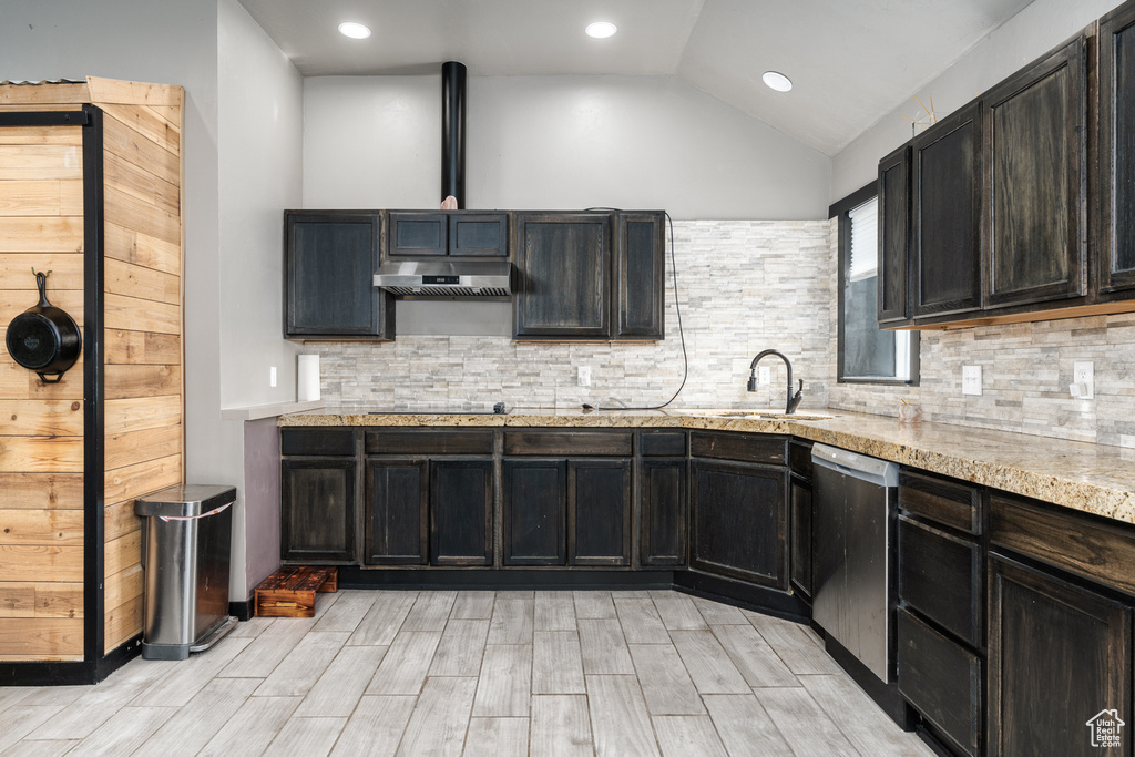 Kitchen featuring dishwasher, a sink, under cabinet range hood, lofted ceiling, and black electric cooktop