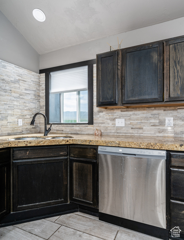 Kitchen with stainless steel dishwasher, decorative backsplash, a sink, vaulted ceiling, and light stone counters