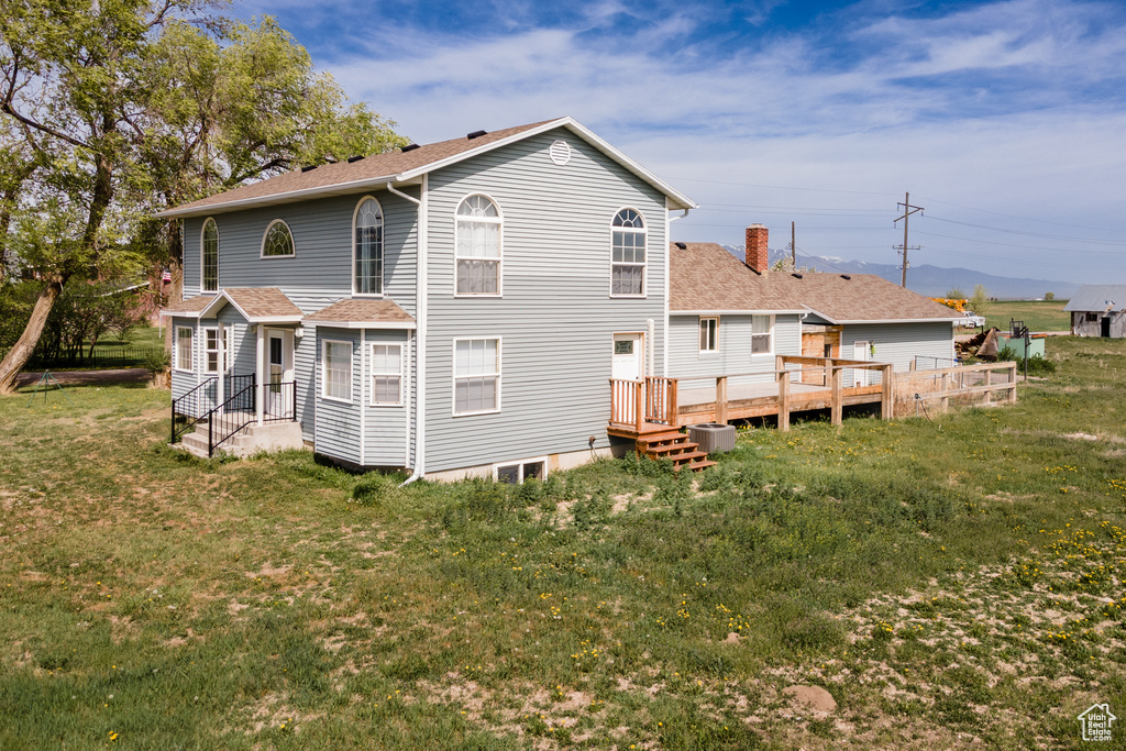 Rear view of property with a yard, a shingled roof, a chimney, and a wooden deck