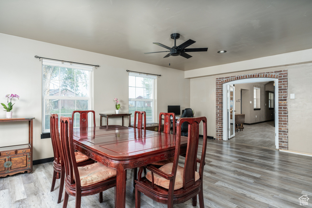 Dining space featuring light wood-type flooring, ceiling fan, arched walkways, and baseboards