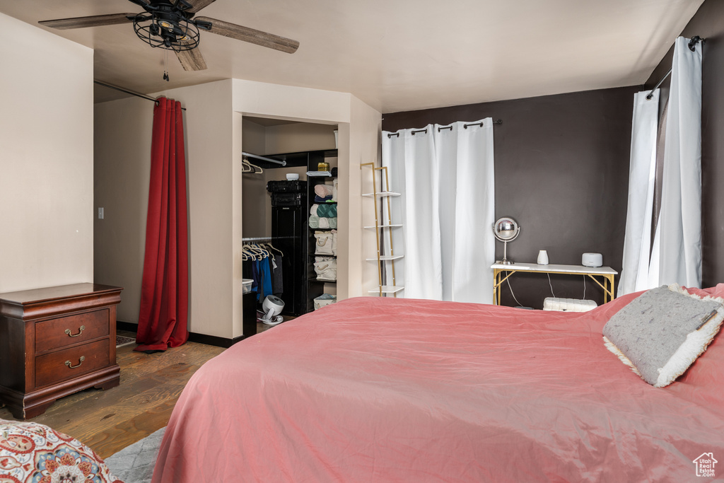Bedroom featuring dark wood finished floors, a walk in closet, a closet, and a ceiling fan