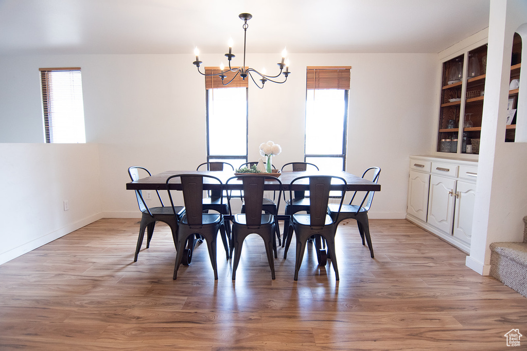 Dining area with plenty of natural light, a chandelier, and light wood finished floors