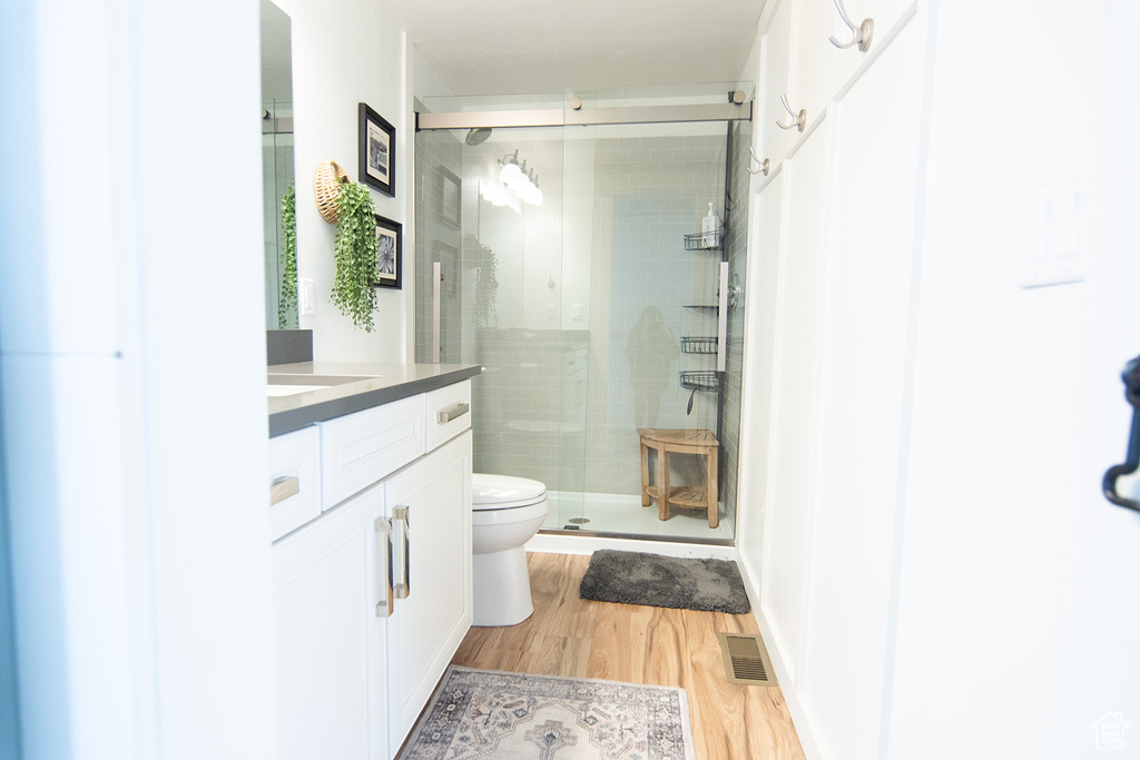 Full bathroom with a stall shower, wood finished floors, toilet, and vanity