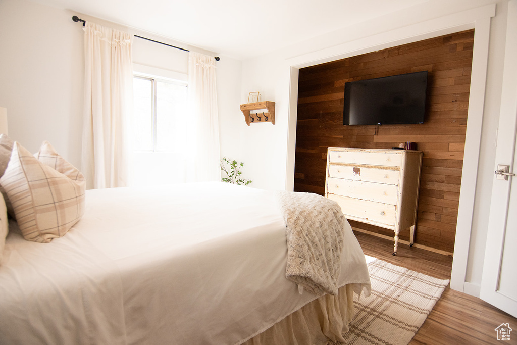 Bedroom featuring wood finished floors, wood walls, and baseboards