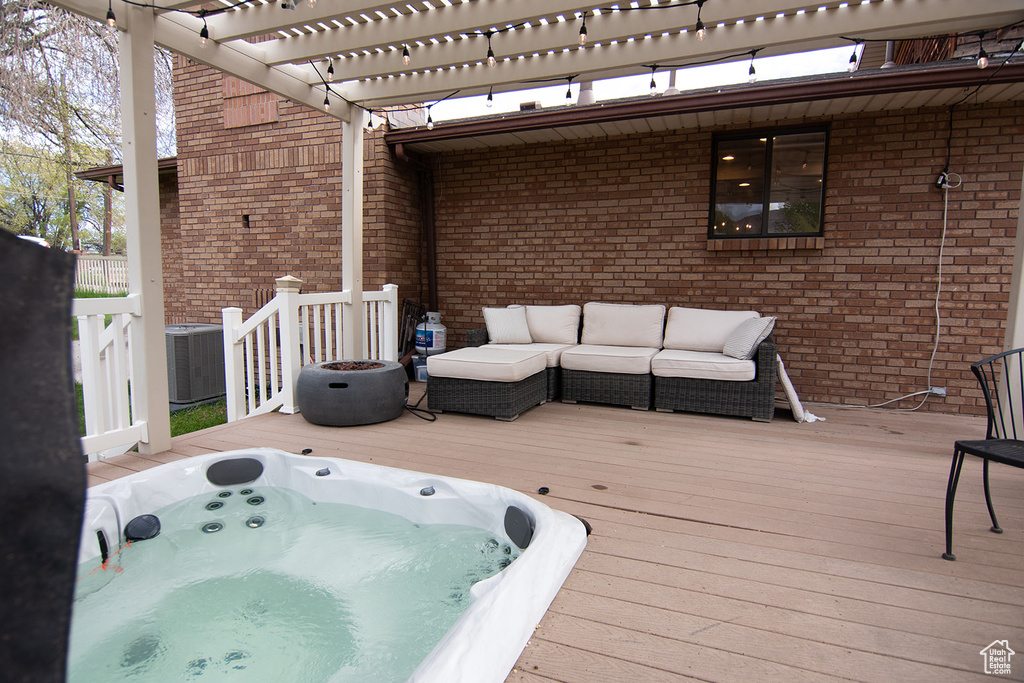 Wooden terrace with outdoor lounge area, a pergola, central AC, and a hot tub