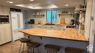 Kitchen with freestanding refrigerator, open shelves, a peninsula, a breakfast bar, and a tray ceiling