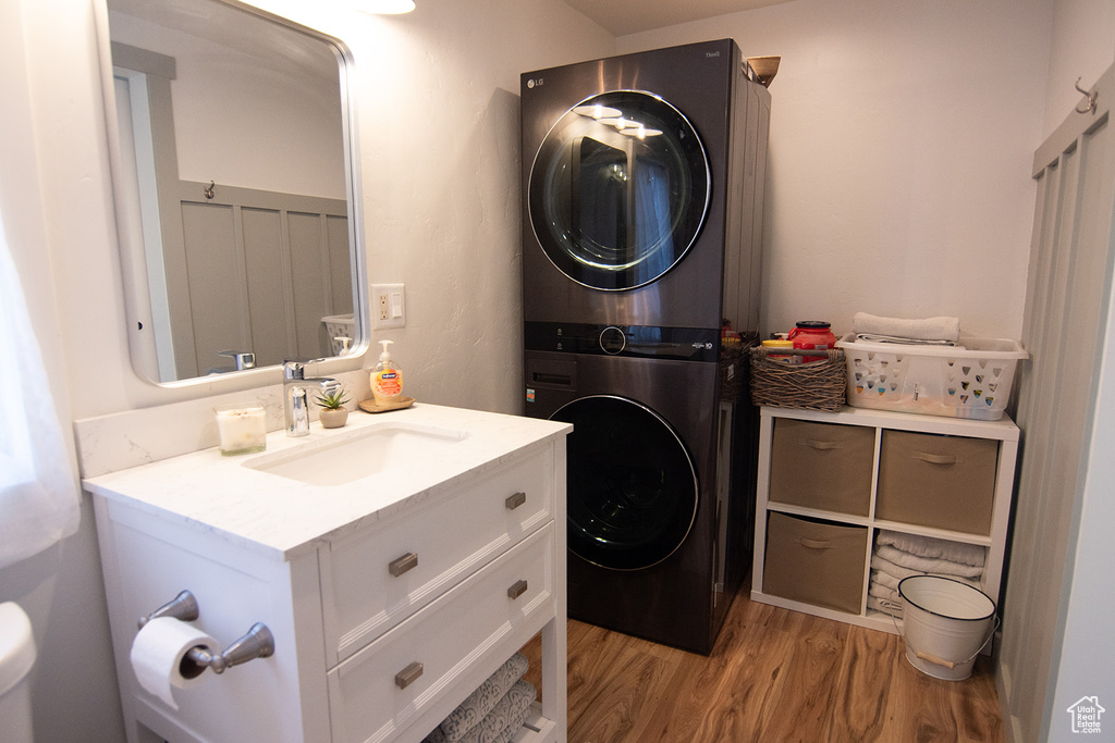 Washroom featuring stacked washing machine and dryer and light wood-type flooring