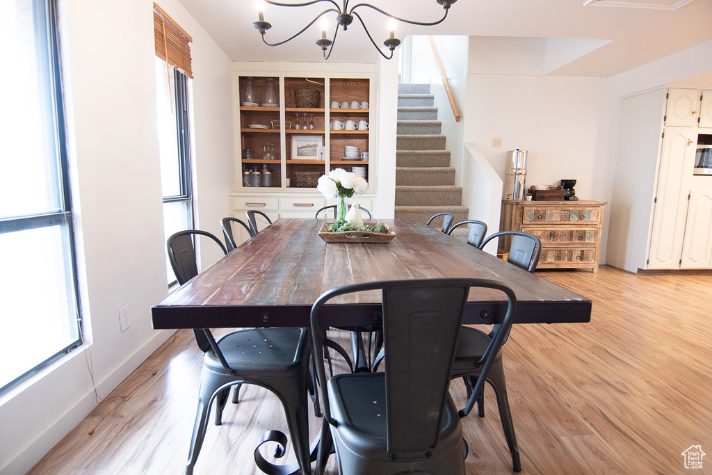 Dining room with a chandelier, light wood-style flooring, and stairs