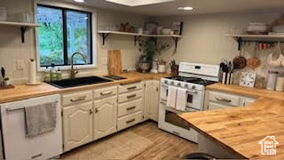 Kitchen with double oven range, open shelves, butcher block countertops, recessed lighting, and a sink