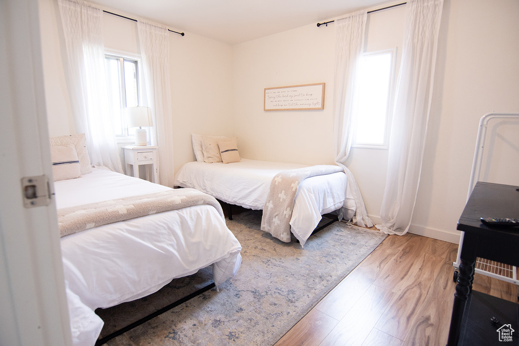 Bedroom with multiple windows, wood finished floors, and baseboards