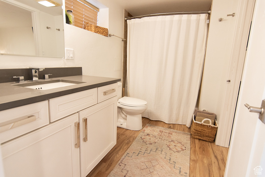 Full bath with toilet, wood finished floors, vanity, and a shower with shower curtain