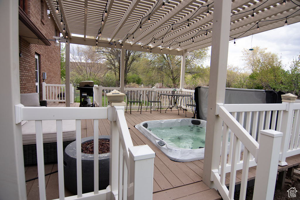 Wooden terrace featuring an outdoor hot tub, a pergola, and area for grilling