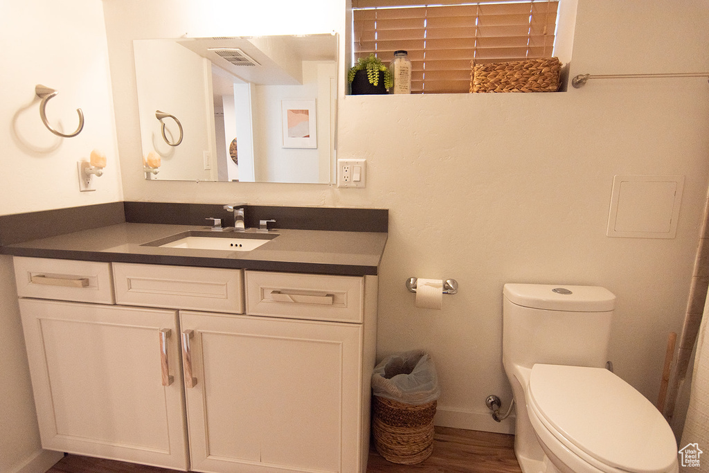 Bathroom featuring toilet, vanity, wood finished floors, and baseboards