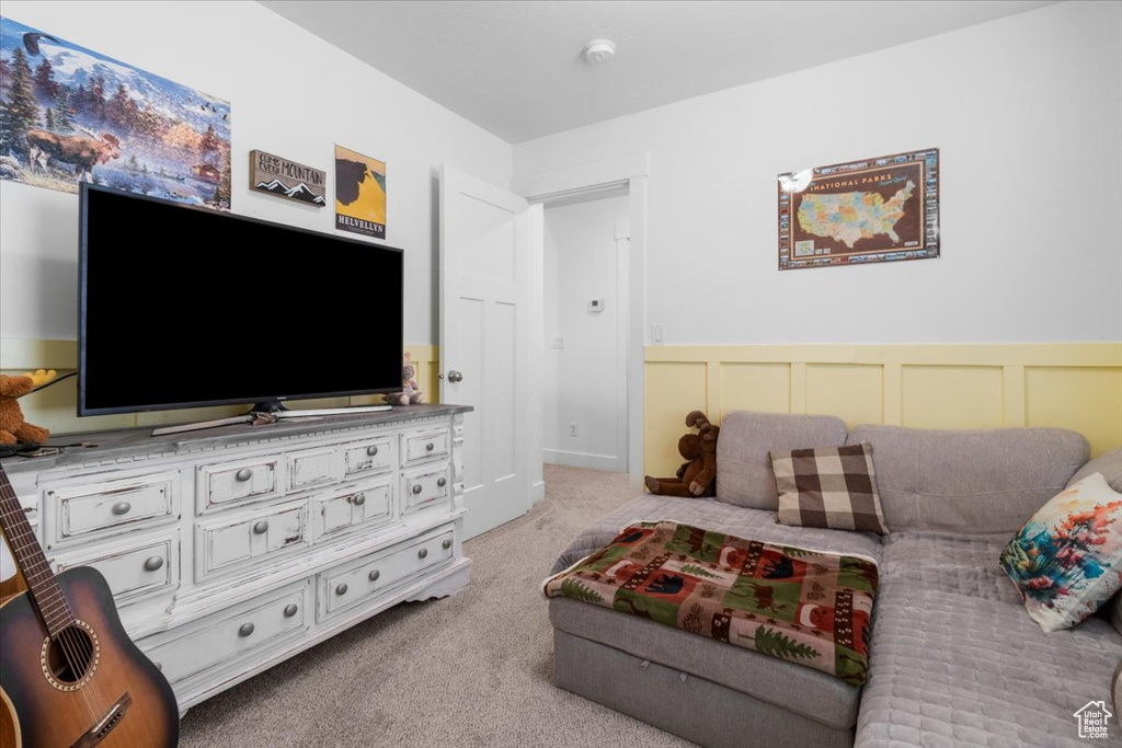 Living room featuring carpet flooring, wainscoting, and a decorative wall