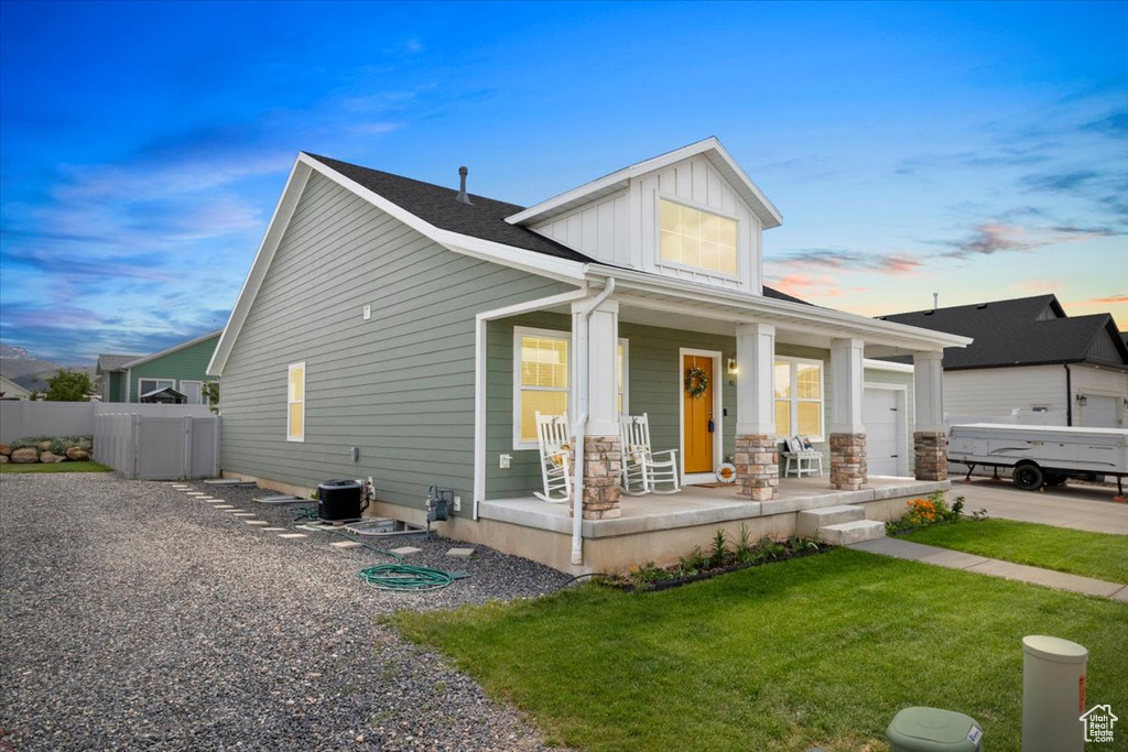 View of front facade featuring covered porch, board and batten siding, and a garage