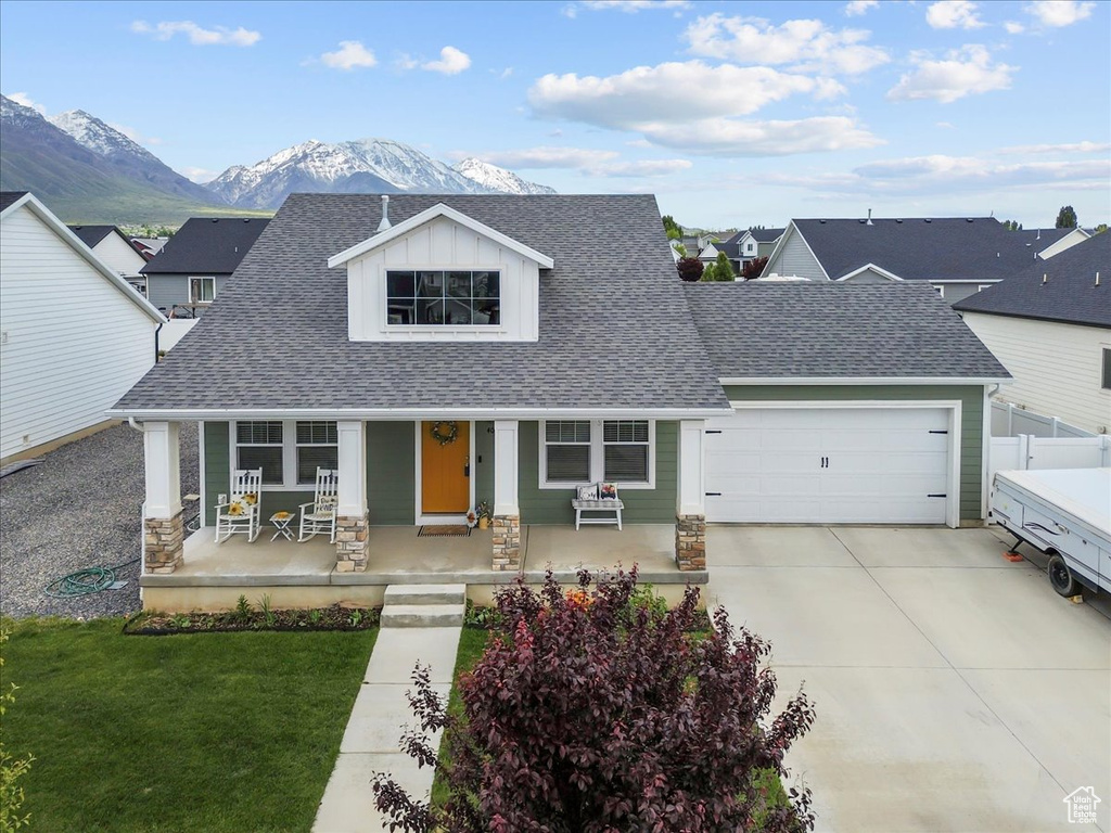 View of front of property featuring a porch, a shingled roof, an attached garage, and a mountain view
