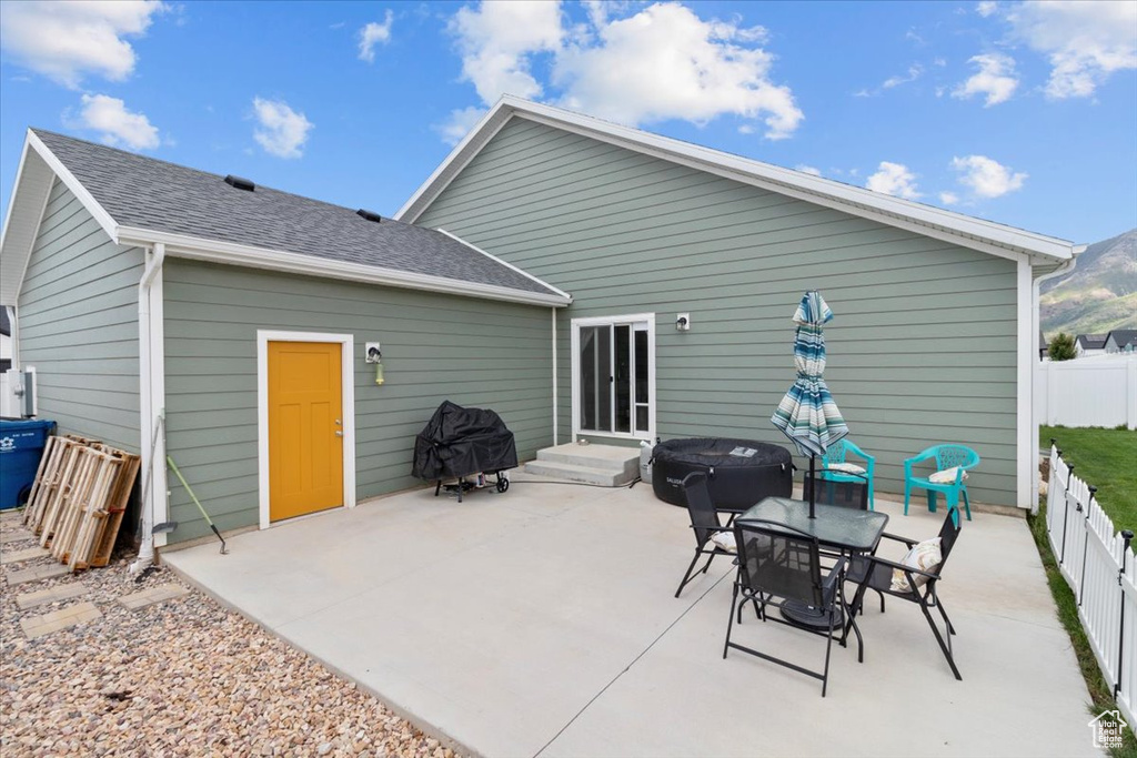 Rear view of property with a patio area and roof with shingles