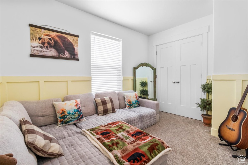 Living area with carpet flooring, a wainscoted wall, and a decorative wall