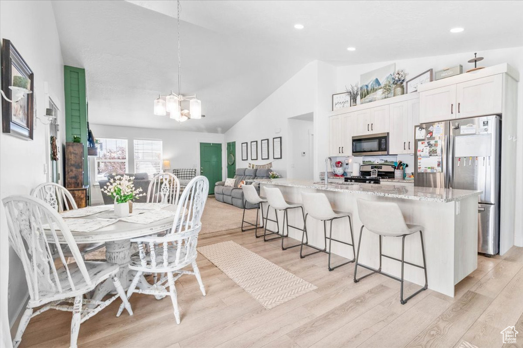 Dining space featuring a chandelier, light wood-type flooring, high vaulted ceiling, and recessed lighting